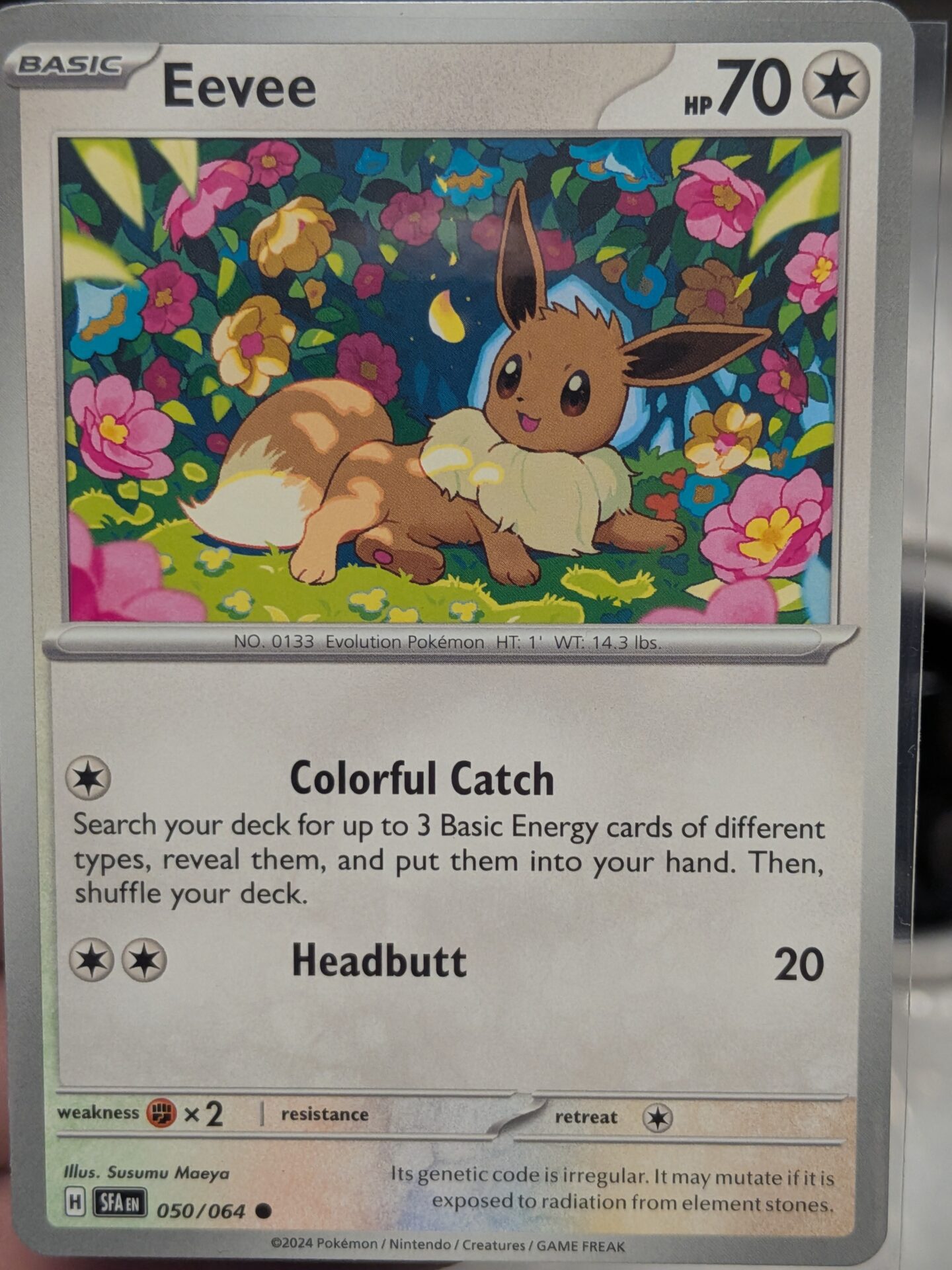 Eevee 050/064 Shrouded Fable card in a flower garden